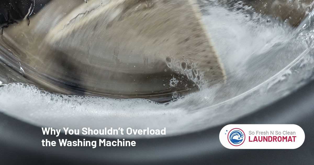 Close-up of a washing machine drum with too many clothes and lots of soap suds inside.