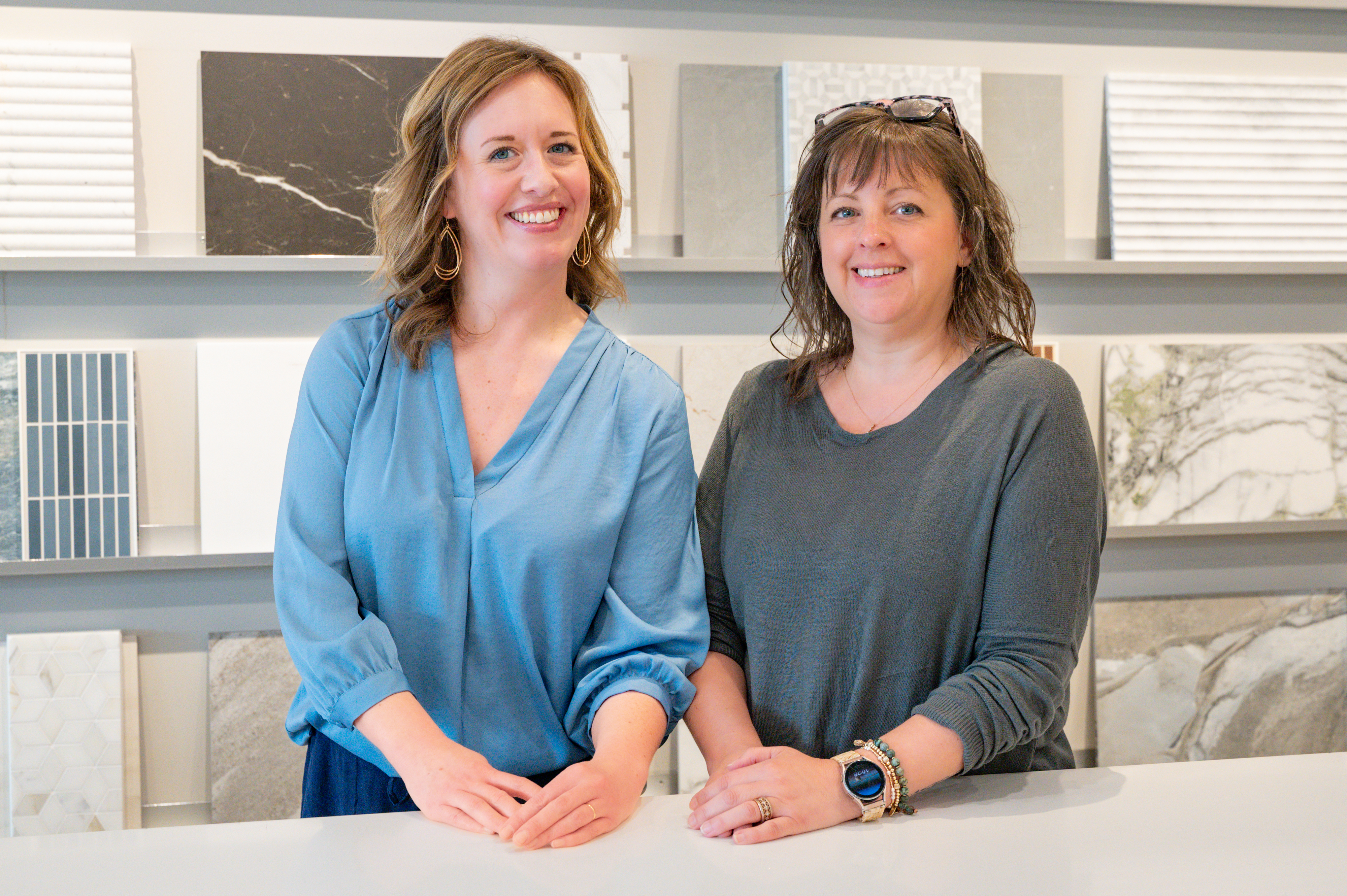 Four people stand smiling behind a white island in a bright, organized walk-in closet.