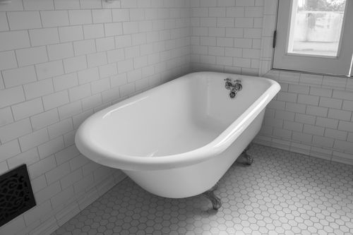 clawfoot tub with whote subway tile wall and hexagon floor tile