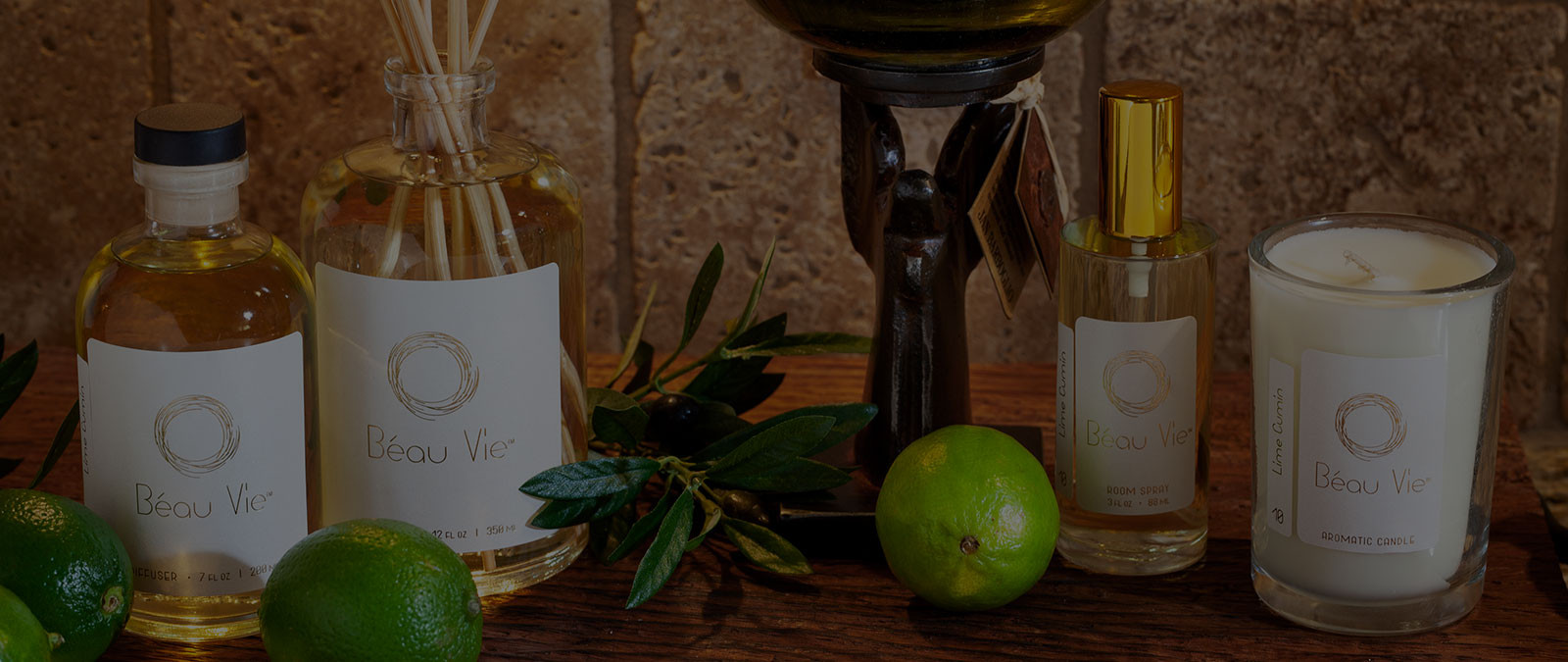 Beau Vie candle, reed diffuser, and room spray arranaged with greenery and limes