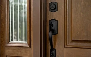 A wooden entry door is slightly open, showing a black handle and glass panel with vertical lines.