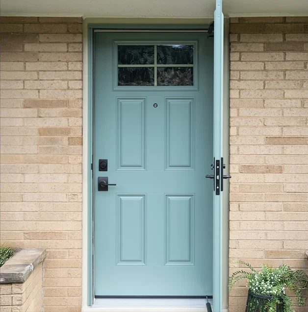 A light blue front door with glass panes, set in a beige brick wall, is partially open.