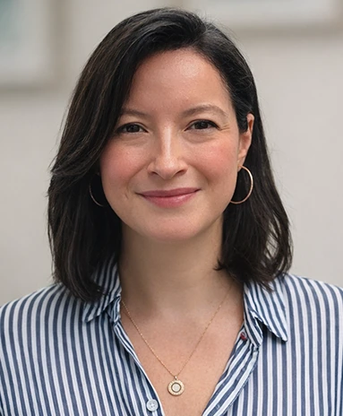 Woman with shoulder-length dark hair, wearing hoop earrings and a striped shirt, smiling.
