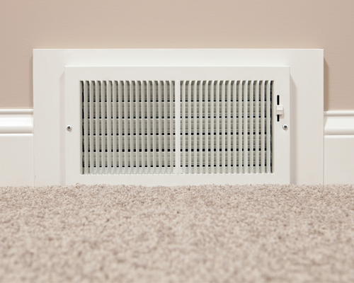 A white air vent and a beige carpet.