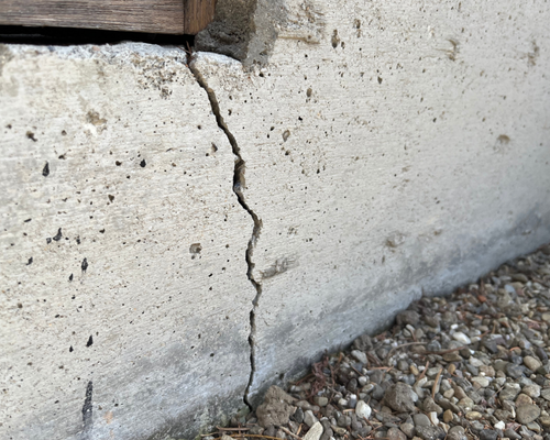 Cracked and stained basement wall with dark marks and discoloration near the base — a sign of foundation failure.