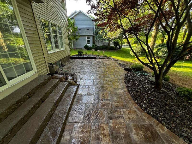 Stone patio with a metal fire pit, curved stone bench, wood fence, and climbing vines.
