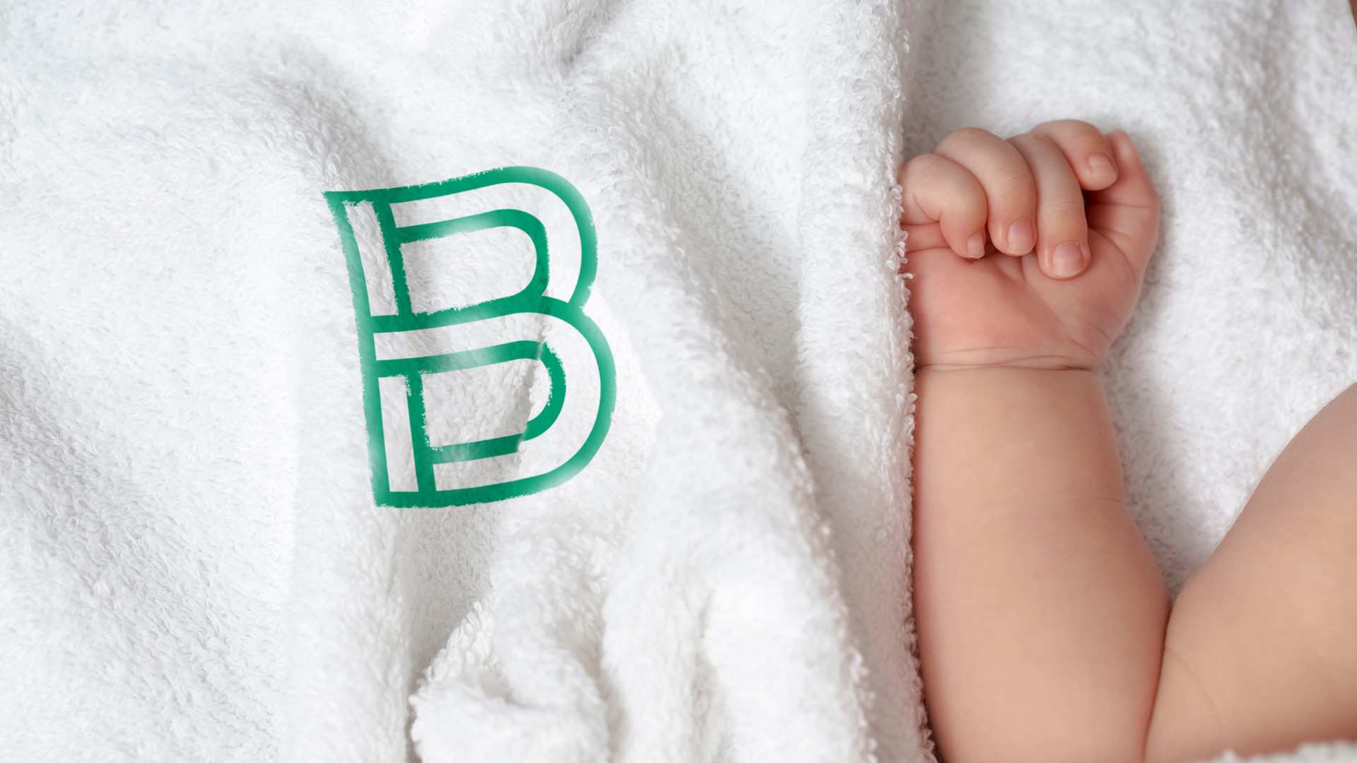 baby hand on white blanket with letter B