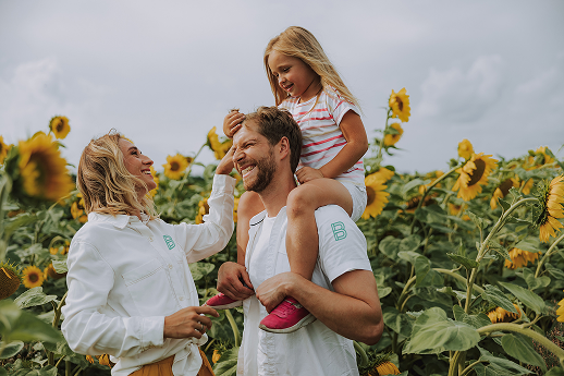 A happy mother and father with their daughter in a patch of sunflowers