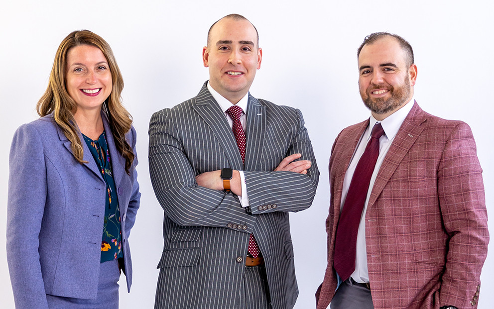 woman and two men posing with white backdrop