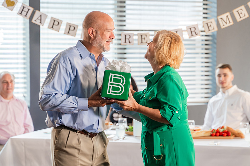 old couple holding present at retirement party