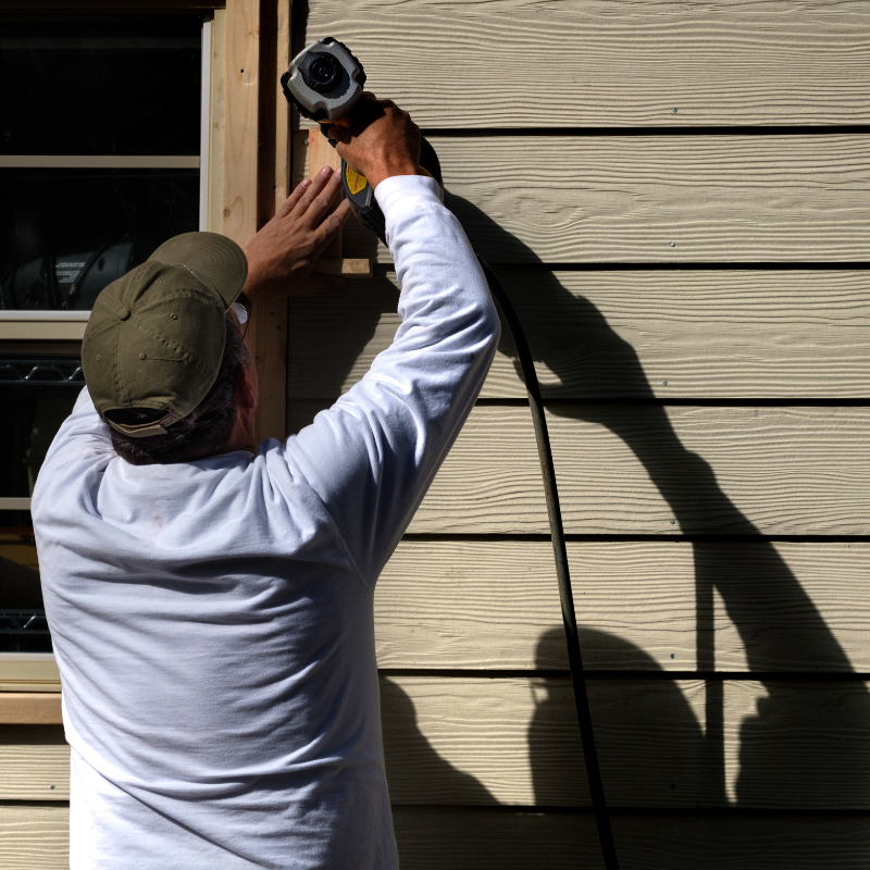 Contractor installing siding on home