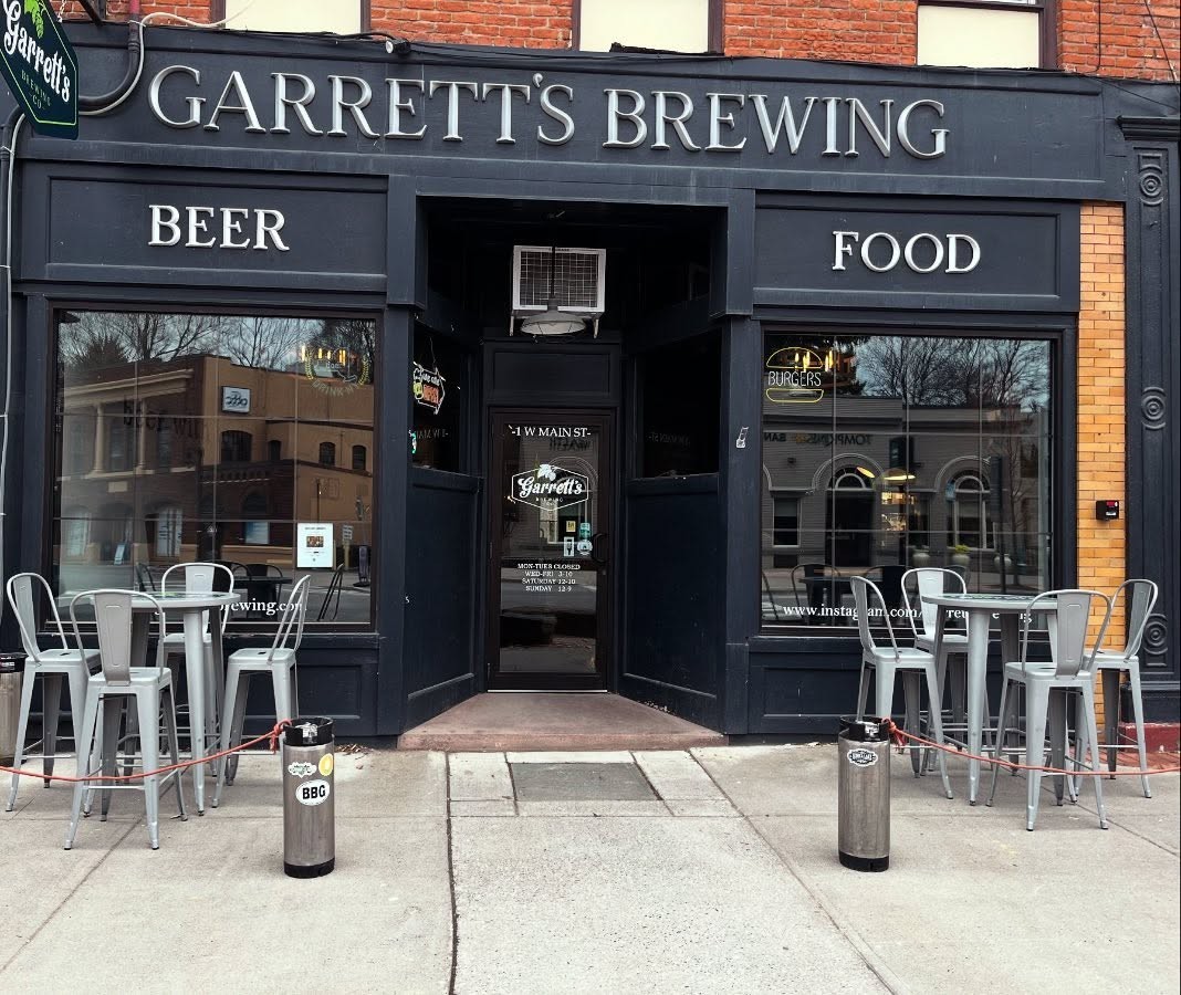 Garretts Brewing storefront with outdoor seating, black facade, and large windows.