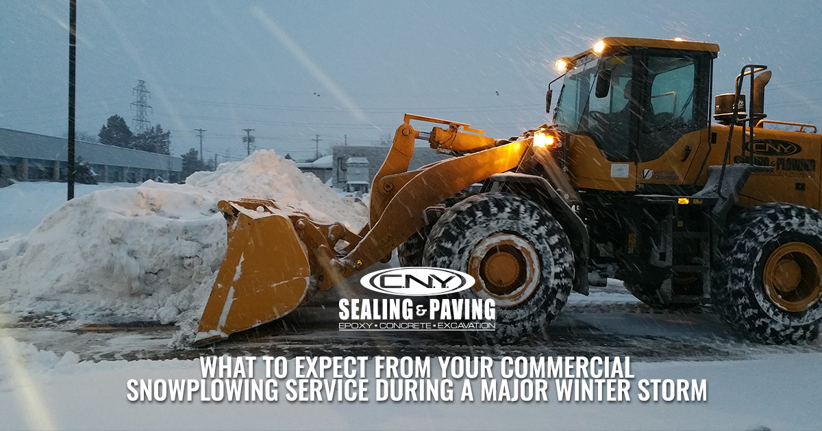 A large snowplow moves snow in a snowy parking lot during a major winter storm.
