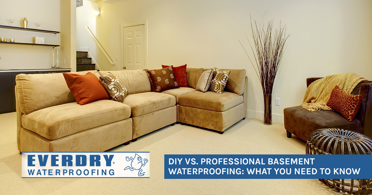 Beige basement living room with sectional sofa, pillows, decor, and Everdry Waterproofing logo.