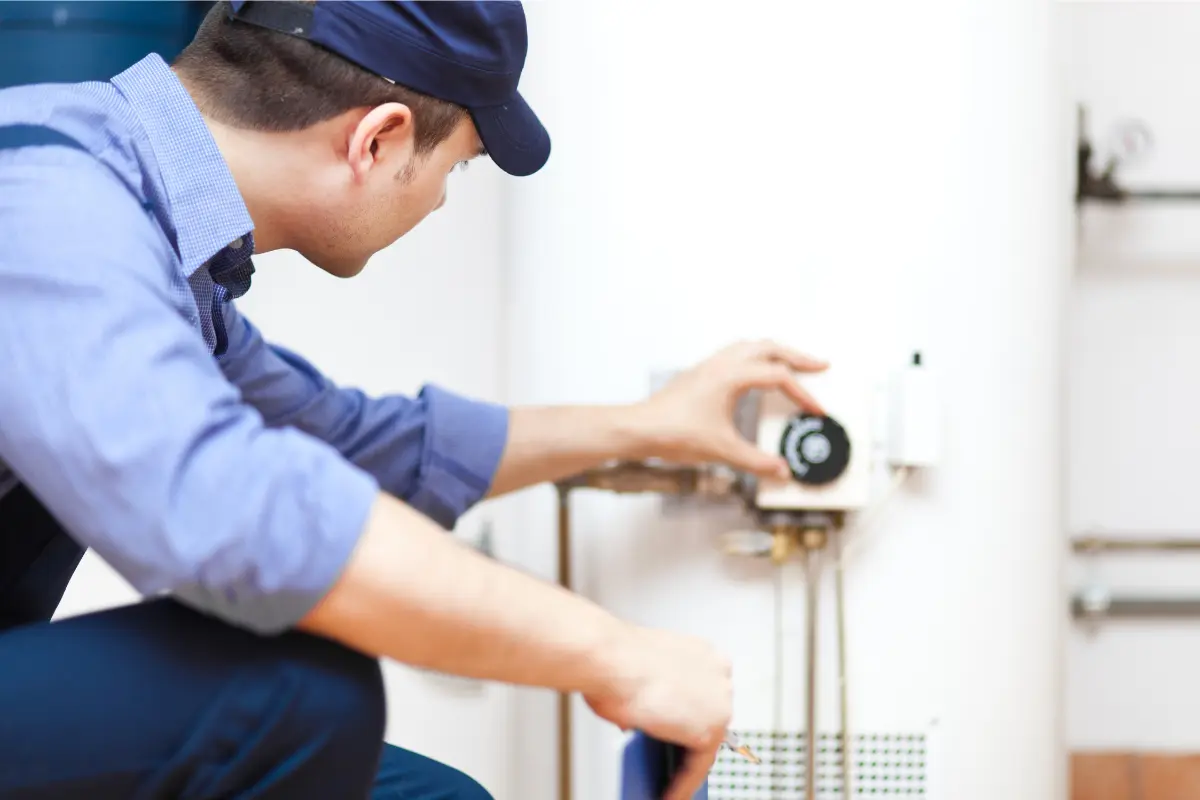 man in blue shirt turning a dial on a water heater