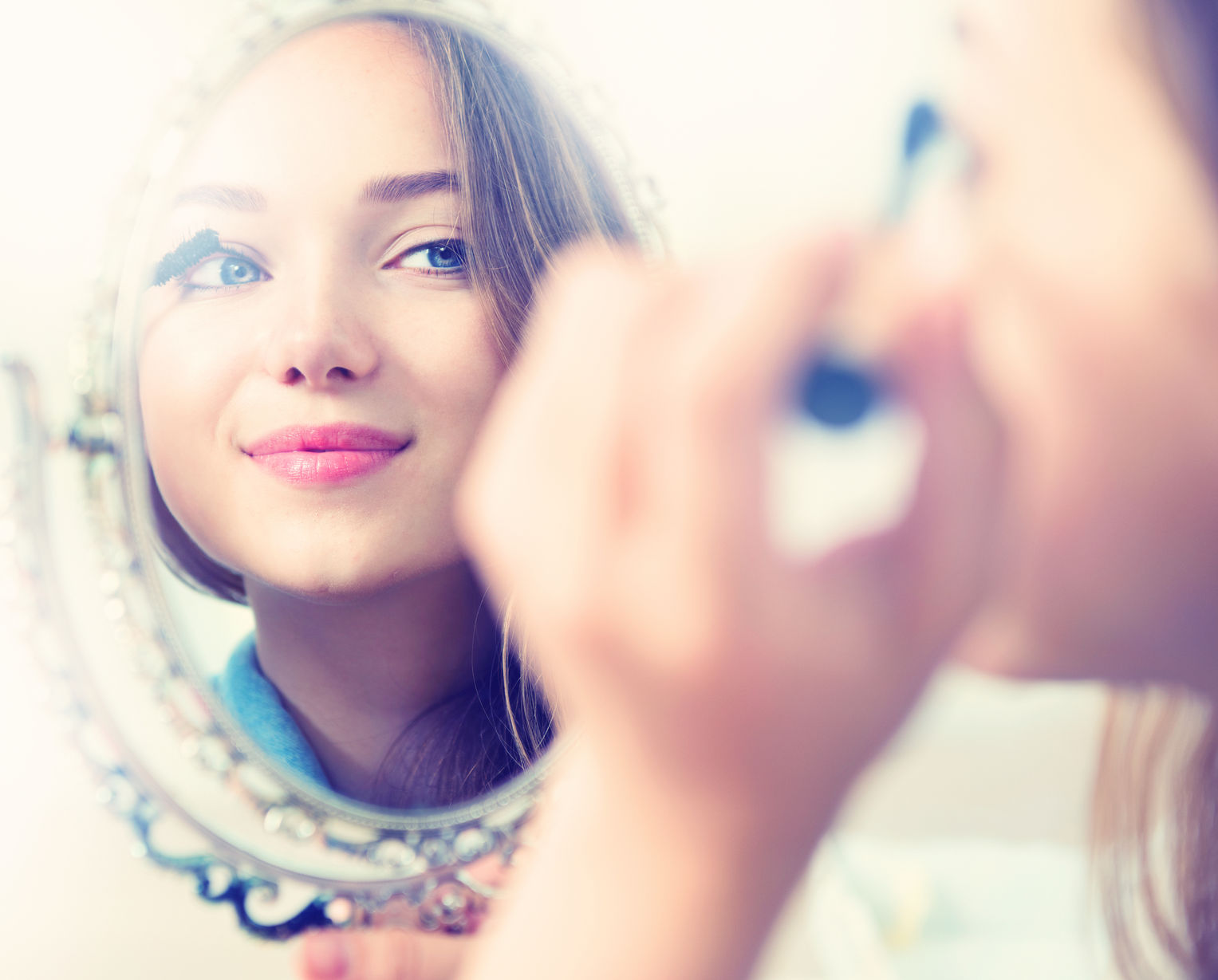 girl putting on makeup in a mirror