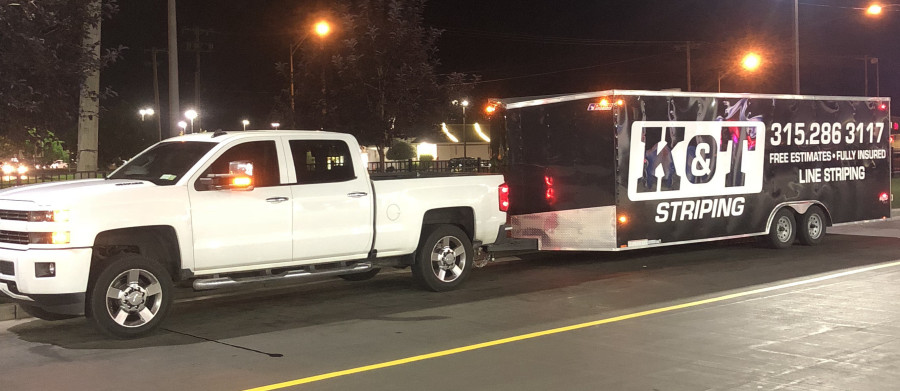 white pickup trick with black trailer with K&T logo