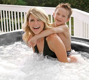 mother with son on her back smiling in bubbling hot tub water