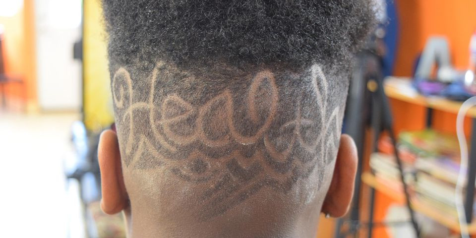 Image of the back of a Black teen's head with the word health shaved into it