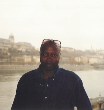 woman smiling wearing a navy blue cap with an orange star and h logo and a green shirt