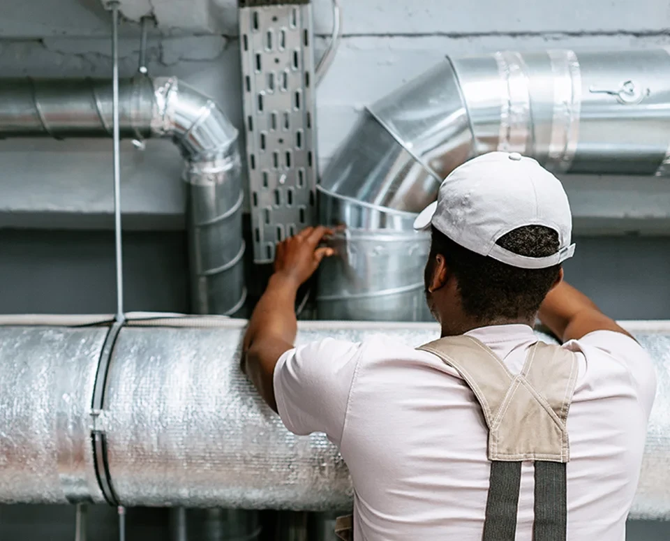Man is white overalls servicing an air duct.