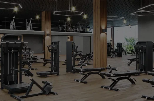 Spacious modern gym with weight machines, benches, and cardio equipment on wood flooring.
