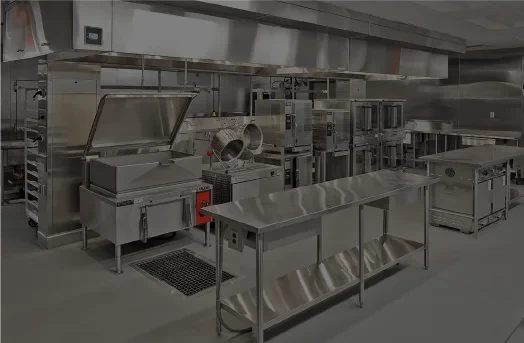 A modern commercial kitchen with stainless steel equipment and preparation tables.