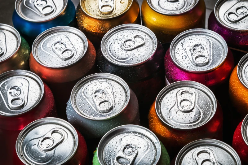 Close-up of various colorful soda cans with condensation, viewed from above.