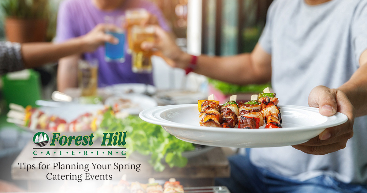 grilled kebabs on a white plate with table of food and drinks in background