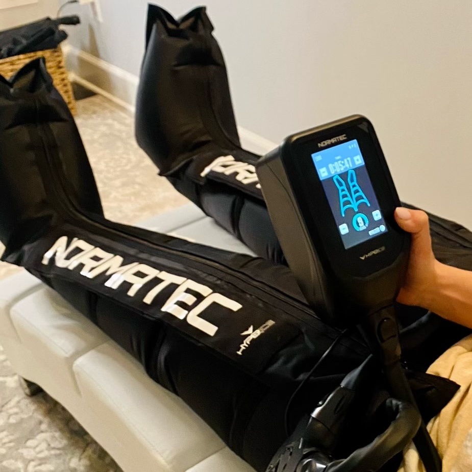 two woman holding hands while doing normatec therapy