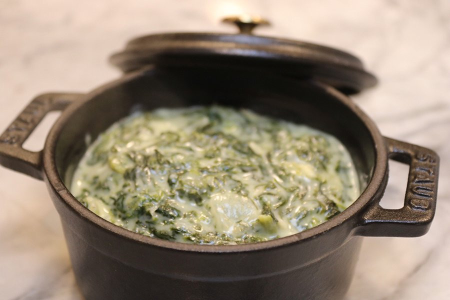 Creamed spinach in cast iron serving dish with lid