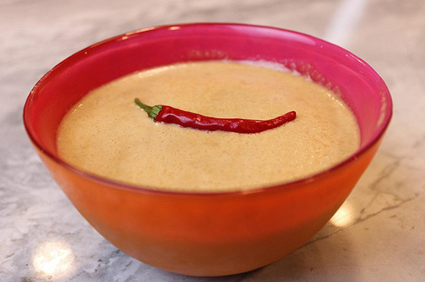 tan sesame ginger dressing in a red glass bowl with a dried chili on top