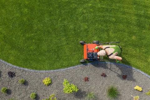 person mowing lawn beside landscaped garden border