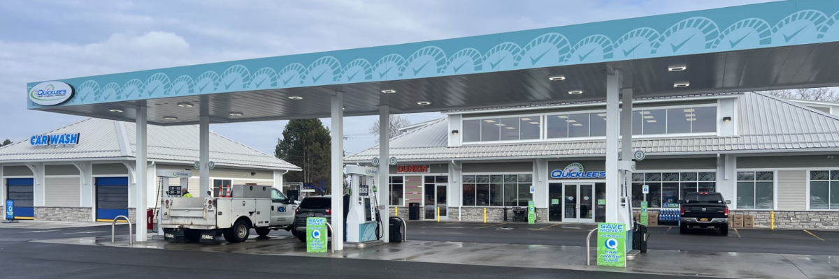 A Quicklee’s gas station with a convenience store and a car wash on a cloudy day.